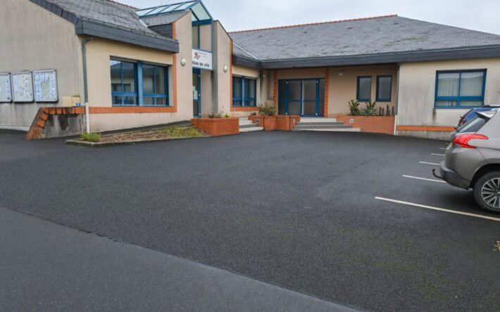 Le parking de la mairie a été refait avec un enrobé perméable. En cas de fortes précipitions, les eaux sont récupérées dans une noue située en contrebas - Crédits photo : Banque des Territoires